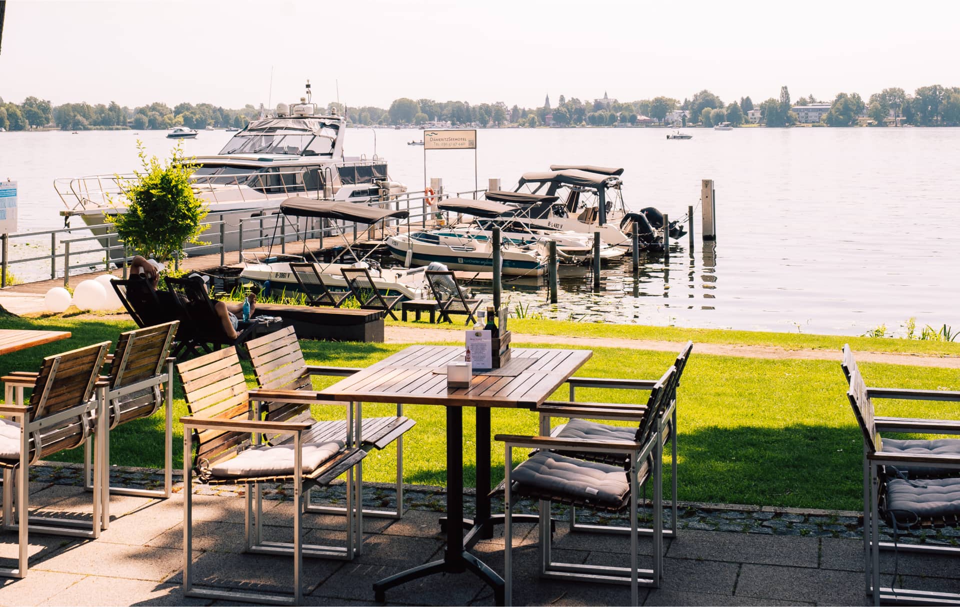 Seeterrasse mit Holzmöbeln und Blick auf Marina, idyllische Gastronomieterrasse