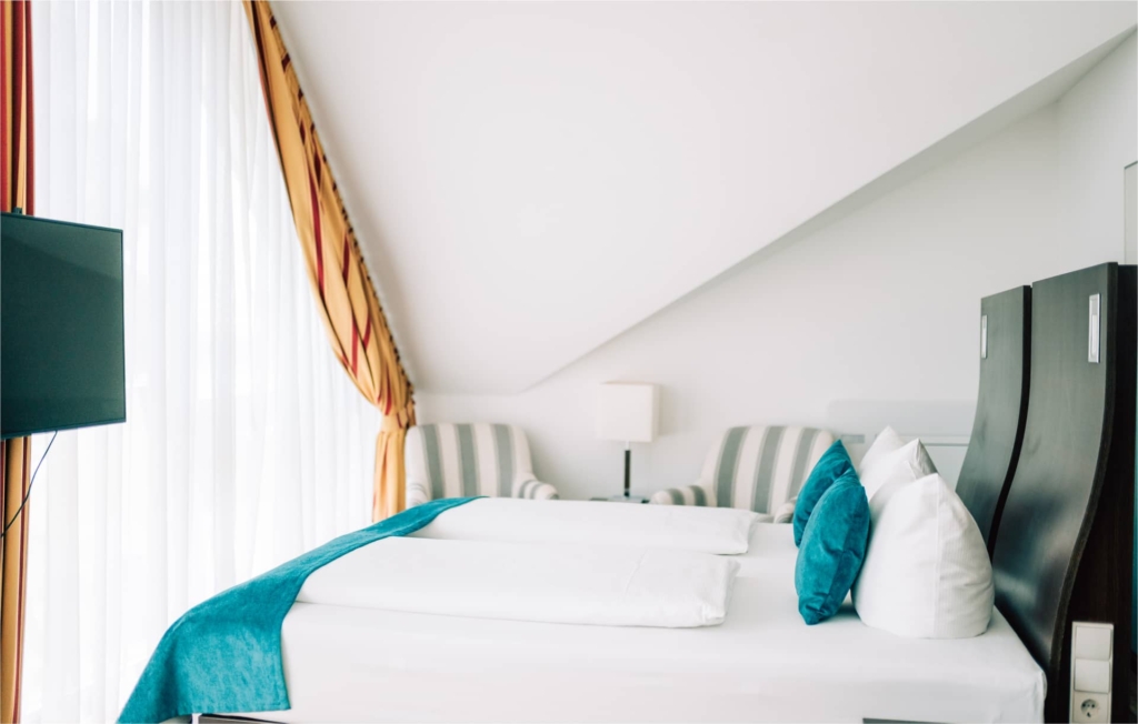 Gemachtes Hotelbett mit türkisen Akzenten und weißer Bettwäsche