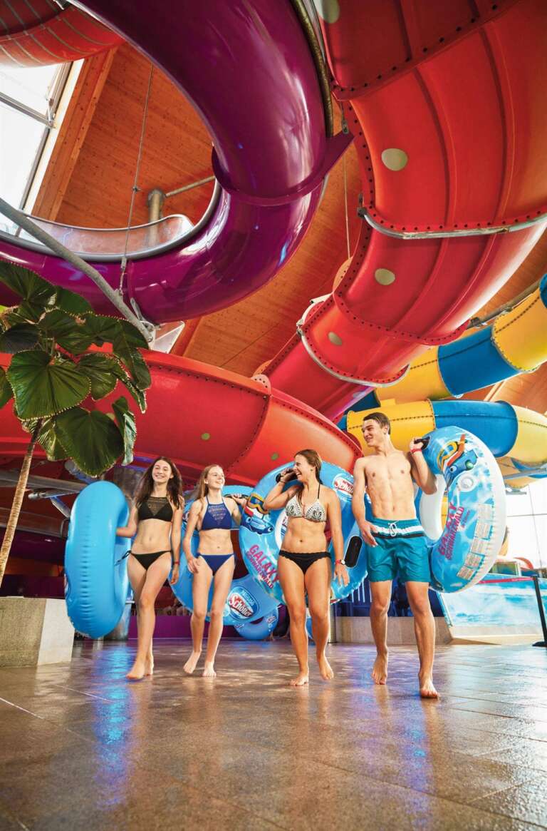 Vier junge Erwachsene mit Schwimmreifen vor den Wasserrutschen im Galaxy Schwarzwald in Titisee-Neustadt