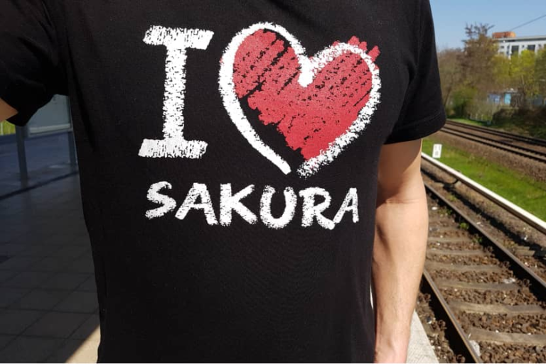 Person mit T-Shirt „I ♥ Sakura“ am Bahnsteig