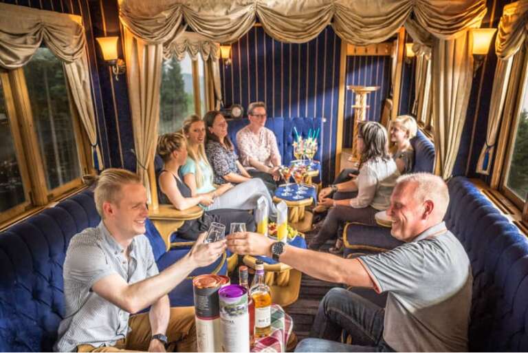 Reisegruppe sitzt gesellig im nostalgischen Salonwagen der Harzer Schmalspurbahnen bei einer Sonderfahrt
