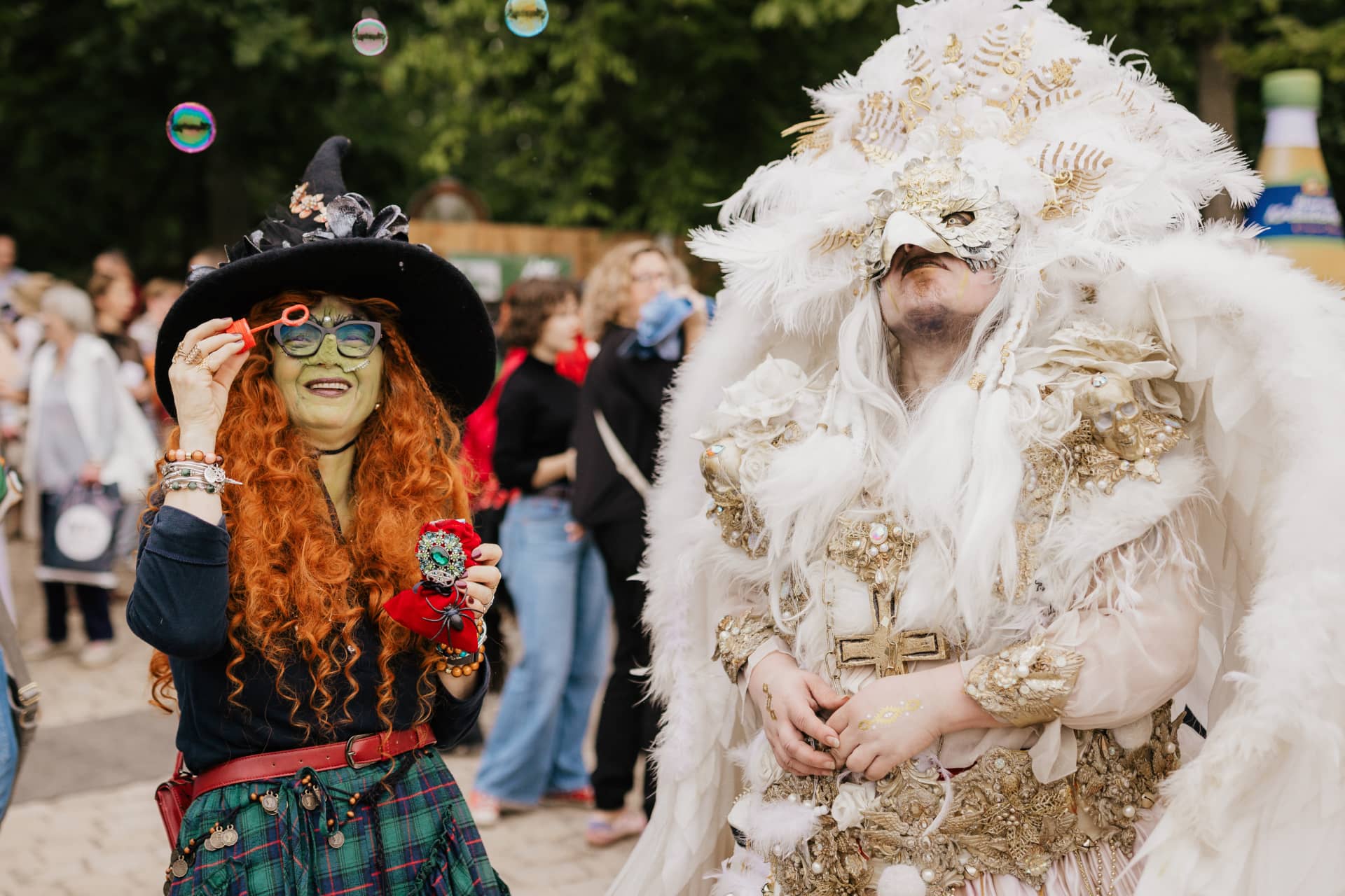 Eine verkleidete Hexe und ein Engel mit Federkleid posieren vor dem Publikum auf dem Theaterplatz.