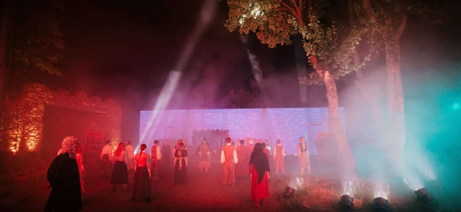 Abendliche Theaterszene mit Nebel und Lichtshow im Harzer Bergtheater, Darsteller in historischen Kostümen.
