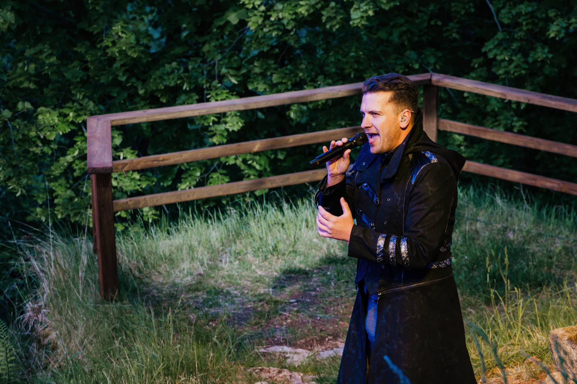 Sänger im schwarzen Kostüm singt mit Mikrofon am Rand der Waldbühne des Harzer Bergtheaters.