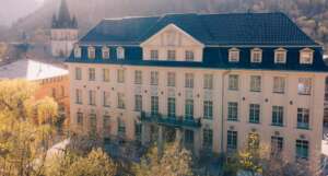Historisches Hotelgebäude H24 Thale tagsüber mit Kirche und Harzlandschaft im Hintergrund