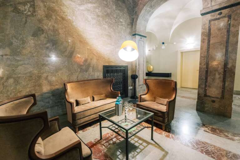 Sitzecke mit Couch, Sessel, Couchtisch und Stehlampe unter Gewölbebogen