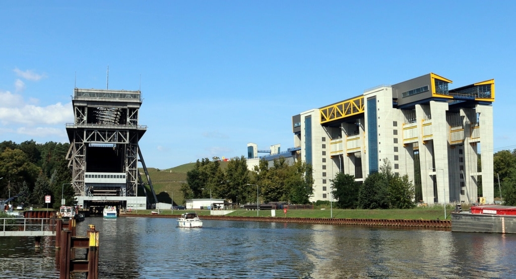 Der malerische Blick auf den Kanal mit Booten wird durch das auf beiden Seiten hoch aufragende Schiffshebewerk Niederfinow unter einem klaren blauen Himmel wunderschön ergänzt und schafft so eine atemberaubende industrielle Kulisse.