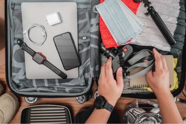 Koffer mit Laptop, Smartphone, Maske, Kamera, Hände greifen Zubehör