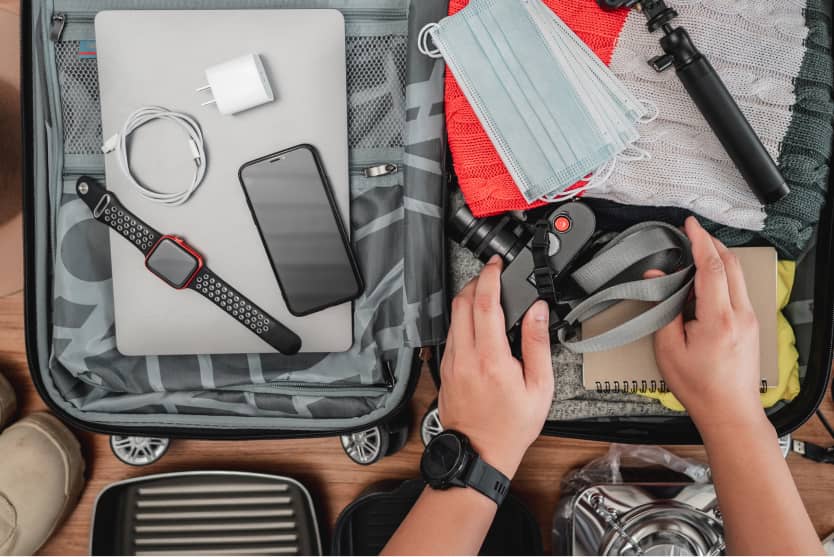 Koffer mit Laptop, Smartphone, Maske, Kamera, Hände greifen Zubehör