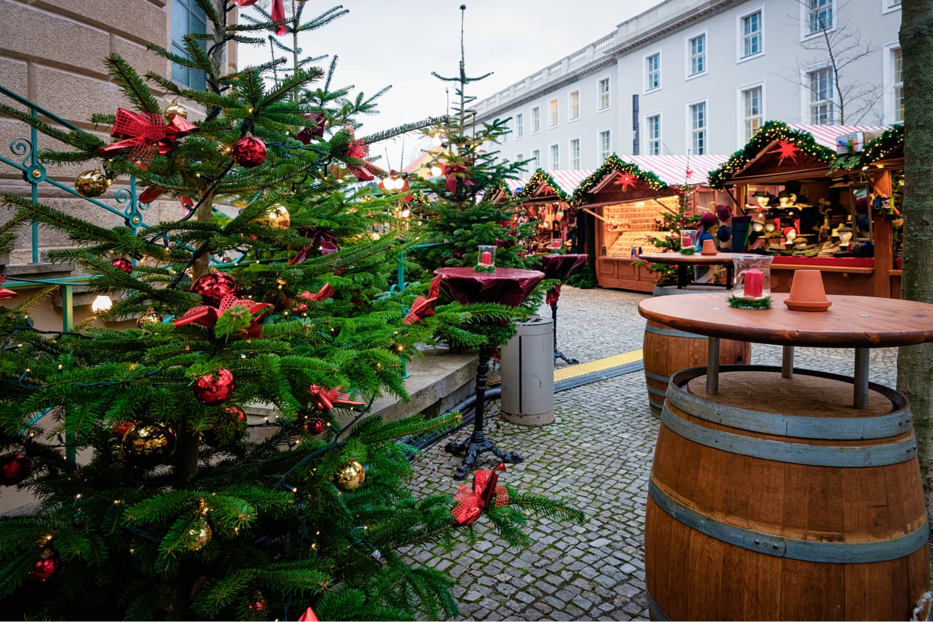 Weihnachtsmarkt mit geschmückten Tannen und beleuchteten HolzbudenWiederholen