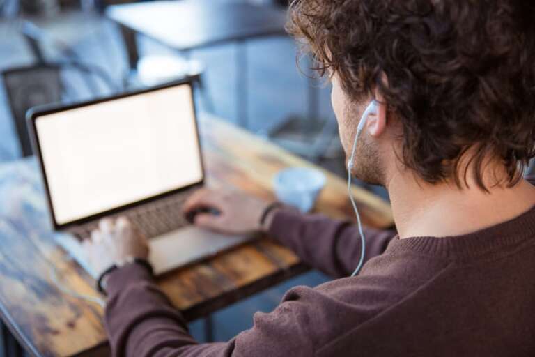 Mann sitzt an einem Tisch und arbeitet an einem Laptop